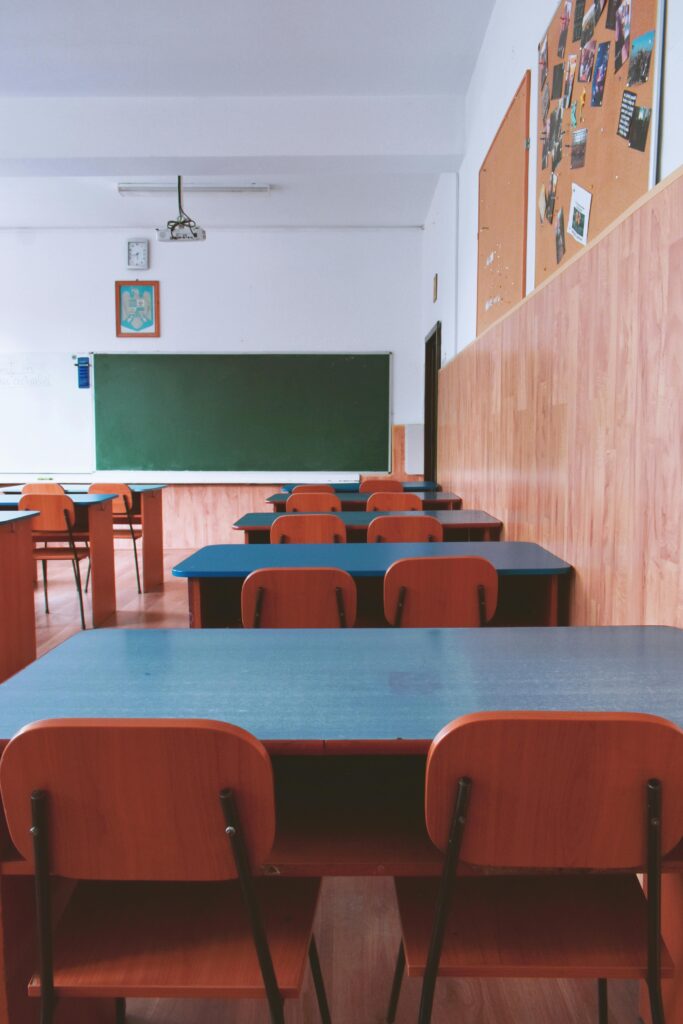 A tranquil empty classroom with wooden furniture and a green chalkboard, perfect for educational themes.