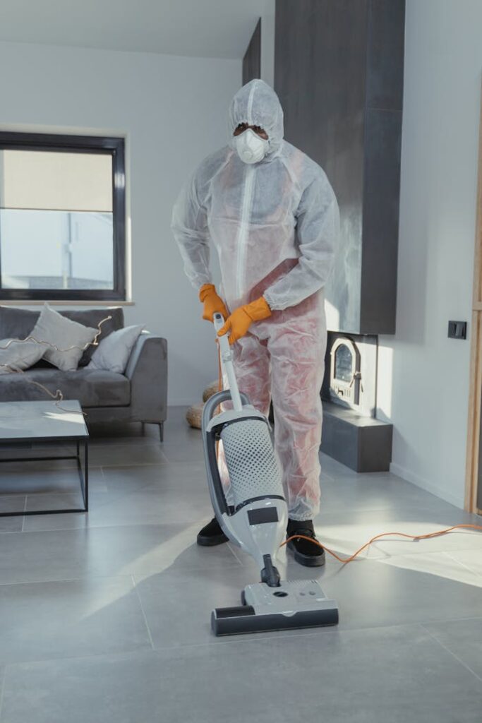 Cleaner wearing PPE with a vacuum cleaner maintaining hygiene in a modern indoor setting.