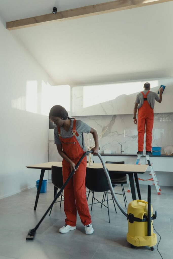 Two cleaners working in a modern kitchen using professional equipment for thorough sanitation.