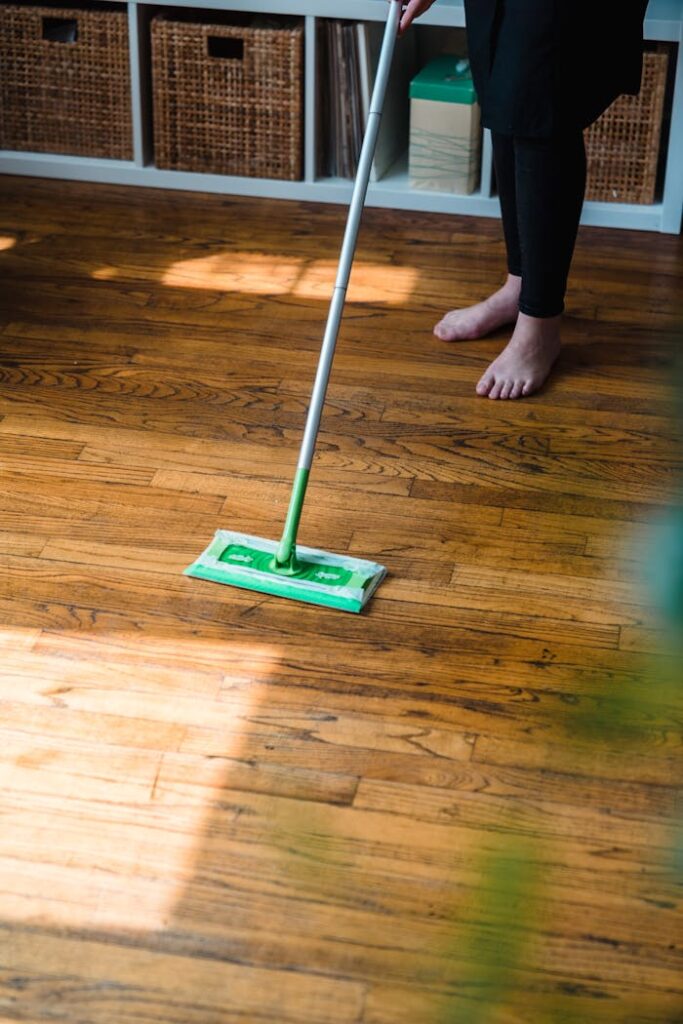 Modern cleaning service image featuring a person with a green mop on a wooden floor indoors.